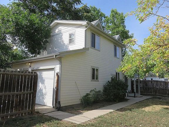 View of the East side of house, from the corner of the yard with the gate open to the garage
