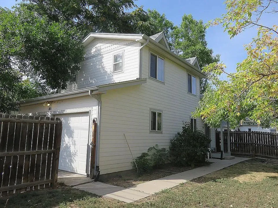 View of the East side of house, from the corner of the yard with the gate open to the garage
