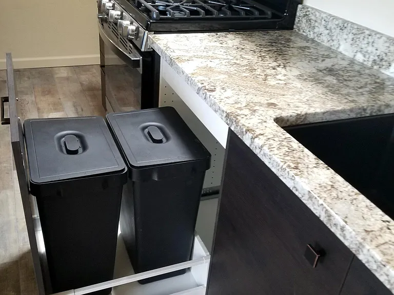 Lidded trash right next to the sink.
