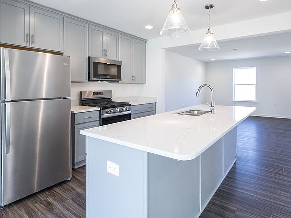 Island kitchen with gray cabinets and stainless appliance in a DRB Homes York II Garage home at the