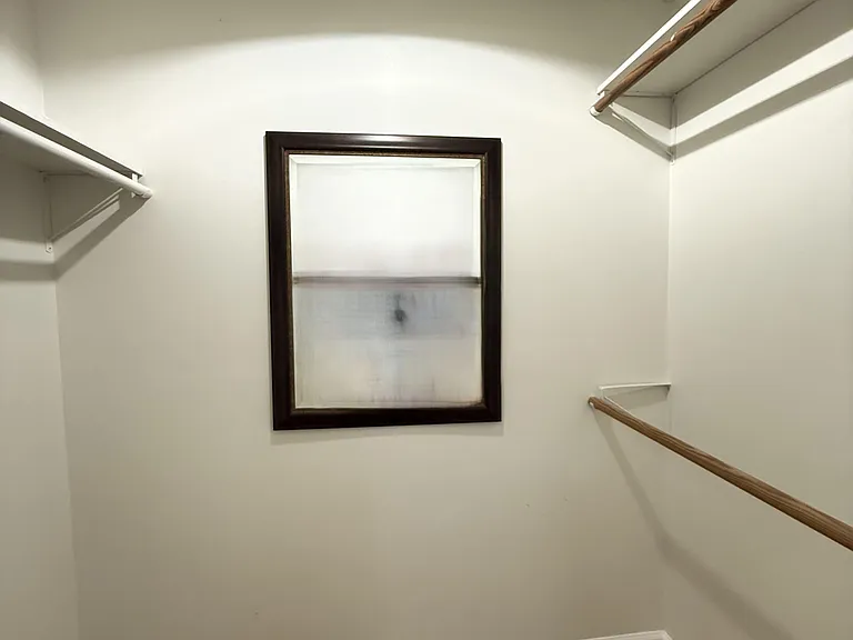 Walk-in closet with built-in hanging rods, mirror and shelving, offering convenient storage and easy organization.