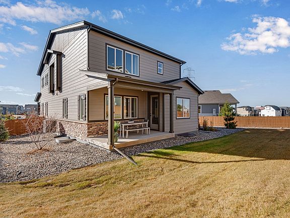 A two-story modern house with a porch, surrounded by a grassy yard and a clear blue sky with scatter