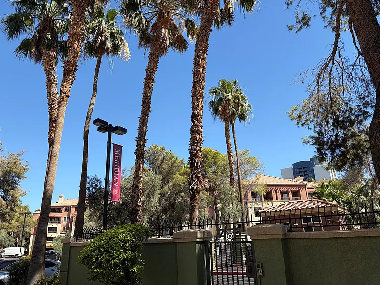 Exterior view of the condo building as seen from the guard gated entrance on Koval Lane. The private balcony overlooks the entrance area, making it easy to spot arriving Uber, Lyft, and other rideshare drivers for convenient pickups and drop-offs.