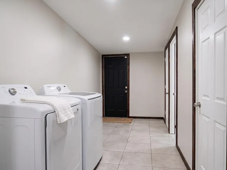 Dedicated laundry area with side-by-side washer and dryer, tile flooring, and easy access off the main hallway.