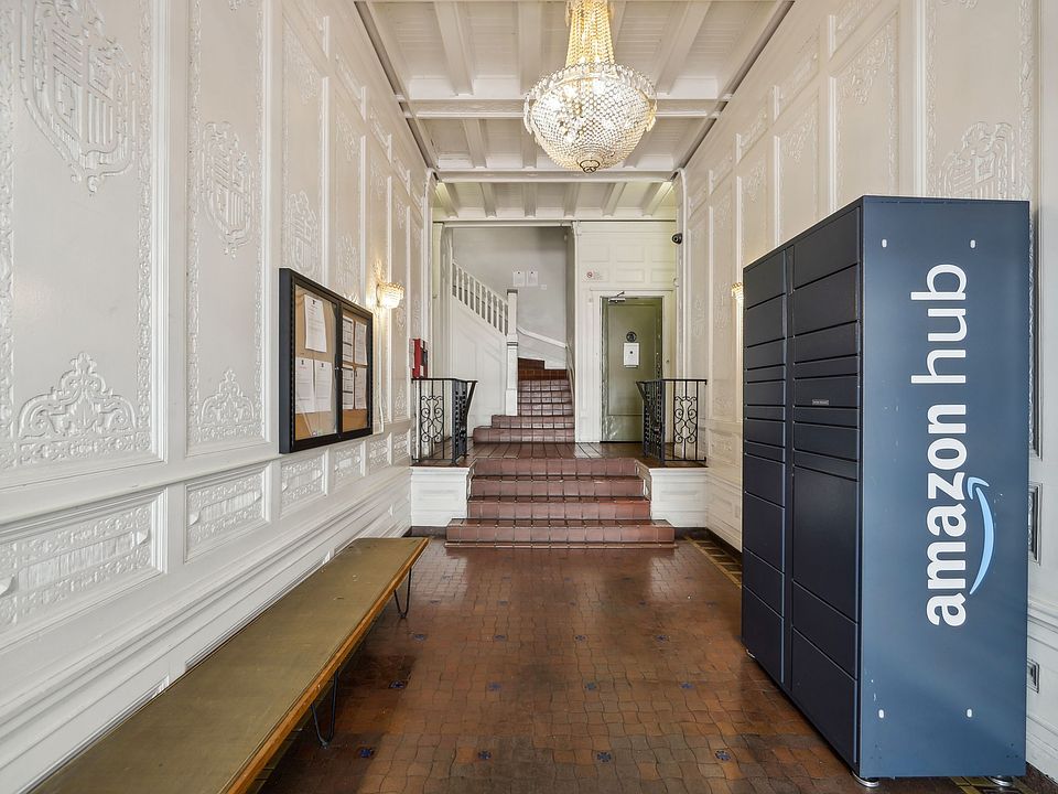 Hallway with ornate walls, terracotta tiles, chandelier, bench, stairs, Amazon Hub locker