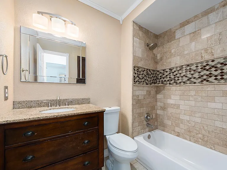 Granite countertop and intricate tile work in shower area.