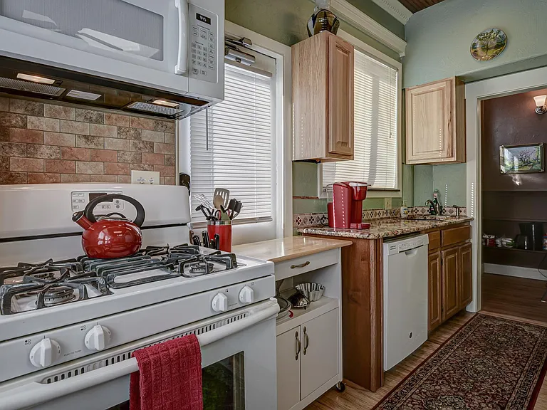 Gas stove, microwave, dishwasher and sink area. Dishes, pots, pans and housewares included.