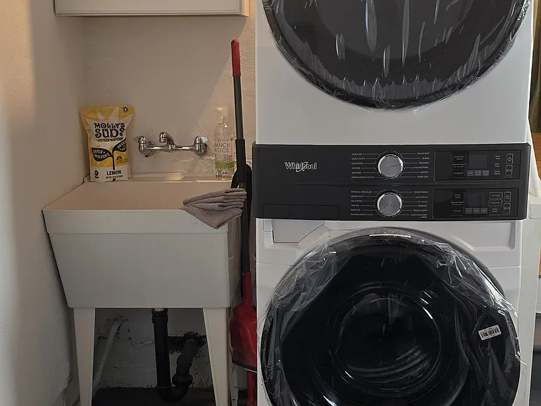 New stacked washer and dryer in garage with wash basin.