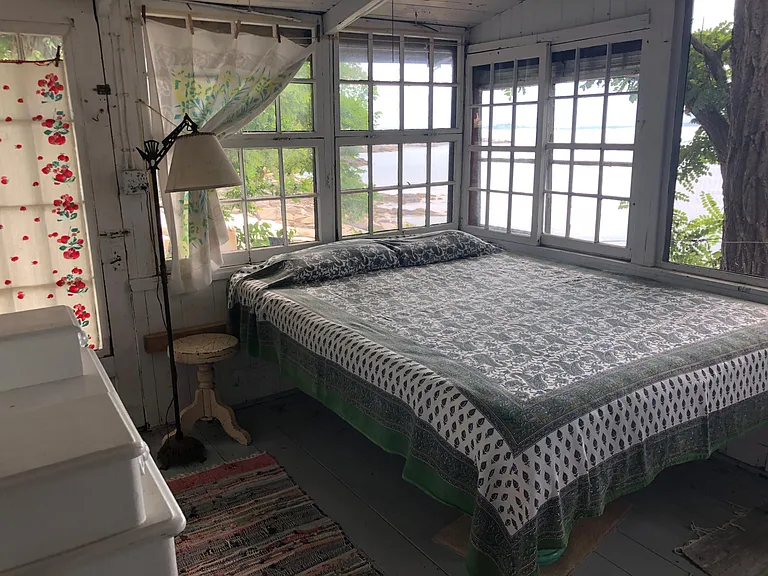 Porch with queen bed. Windows are oversized, freshly screened and open fully to enable air flow that travels through the first level and creates a feeling of bringing the outside inside, while being protected from the elements.