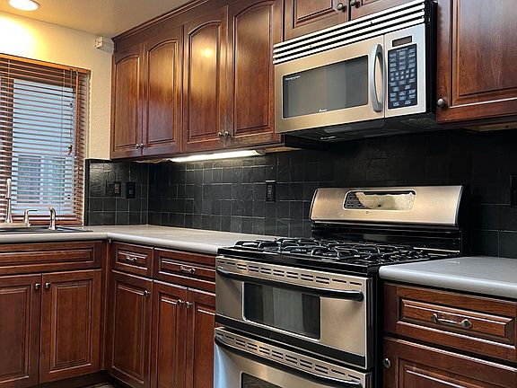 Rich, cabinetry in the kitchen with stainless steel stove/oven and updated countertops