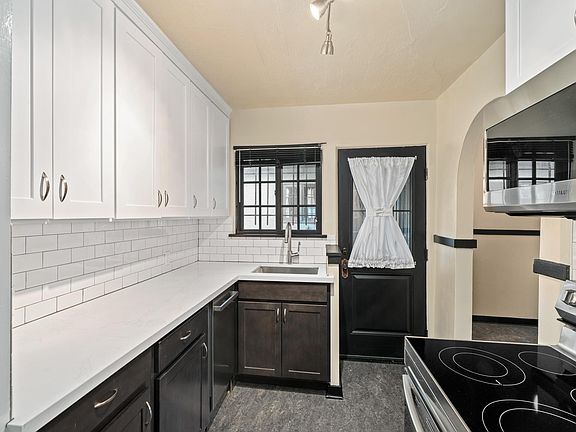 New kitchen with a deep stainless steel sink, dishwasher, stainless steel convection over, overhead microwave. Ahead is the private kitchen entry and to the right of the door is the windowed breakfast room.