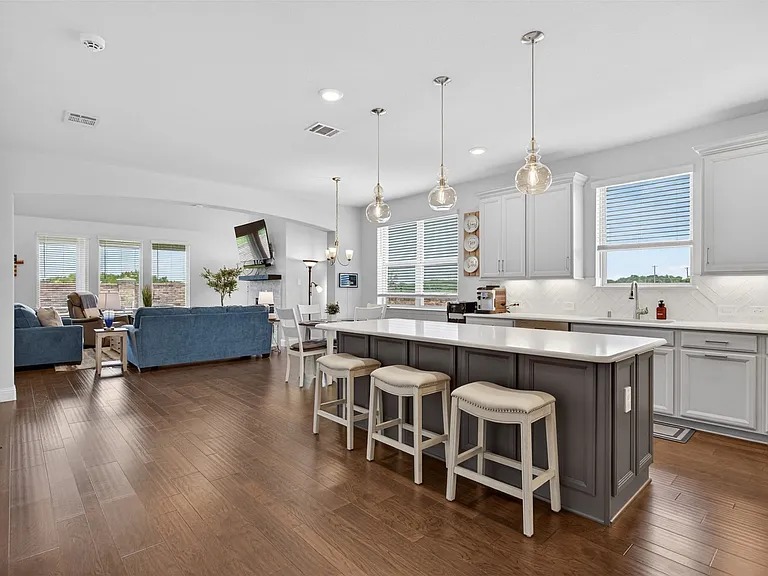 Spacious kitchen featuring a large island with seating, white shaker-style cabinetry, light countertops, and a white subway tile backsplash