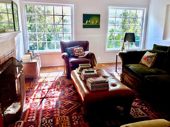 Bright spacious living room with large bay windows has tree-
