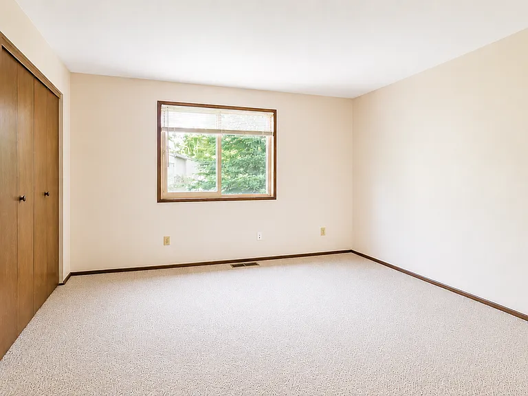 Second bedroom featuring a large closet and a window overlooking the side yard