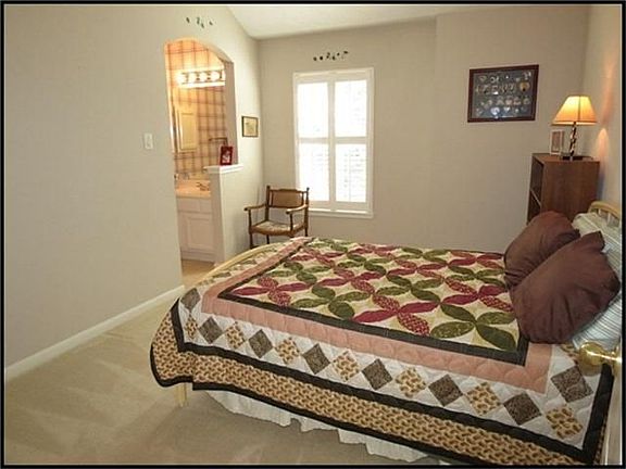 Fourth bedroom upstairs has arched doorway leading to second bathroom vanity area.