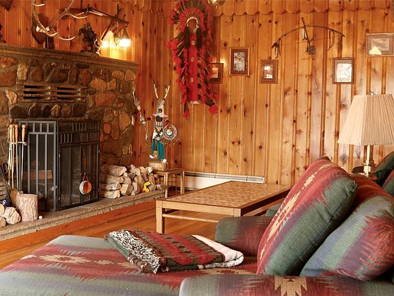 Original rock work hearth around the wood burning fireplace complements the amazing pine wood paneling.