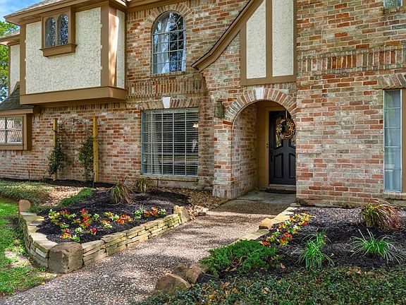 The quaint entrance is flanked by beautiful landscaping and fresh color.