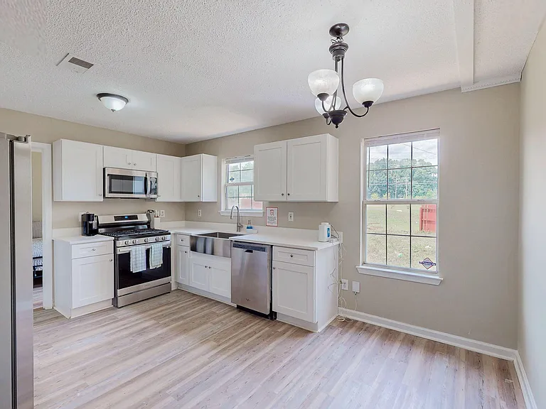 Efficient eat-in kitchen with white cabinetry, stainless appliances, double-basin sink, and large windows for outdoor views.