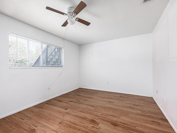 Bedroom with a cieling fan and wood vinyl flooring.