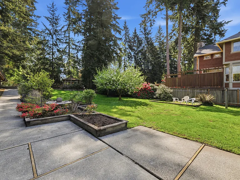 Park-like backyard with cedar gazebo, raised garden beds, and wide lawn