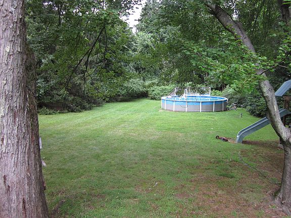 Flat backyard with above ground pool with deck