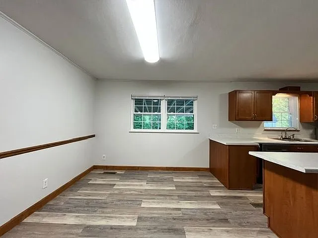 Bright and freshly updated eat-in kitchen and dining area featuring durable wood looking LVP flooring, natural paint, warm wood trim throughout. The space offers abundant natural light from multiple windows overlooking a covered outlook area. Open layout 