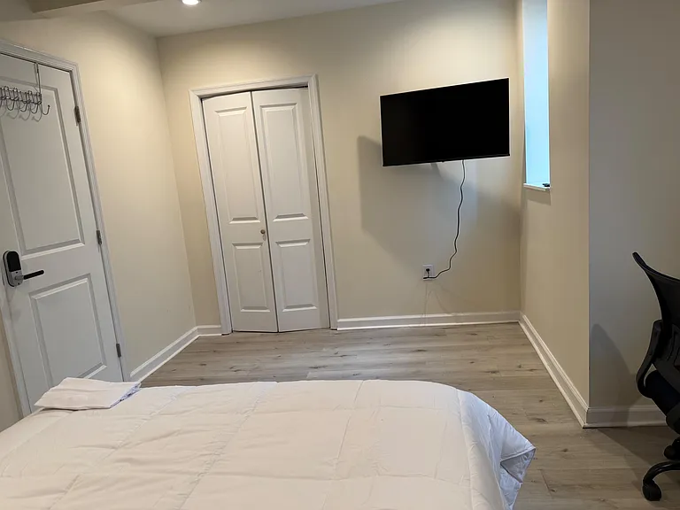 Private bedroom with plank-style flooring, a closet for storage, and a wall-mounted TV; nearby window brings in natural light
