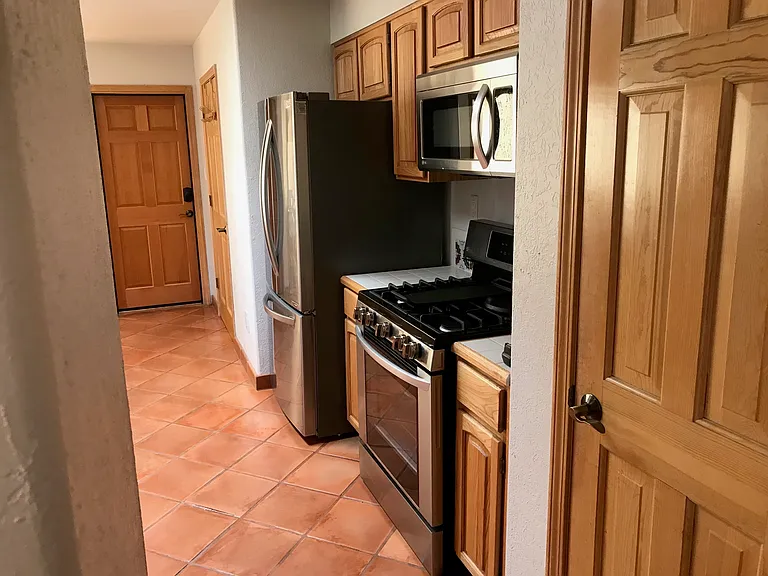 Stainless LG French door fridge, range (natural gas) and large microwave oven ... large pantry door visible in foreground, door to garage in distance