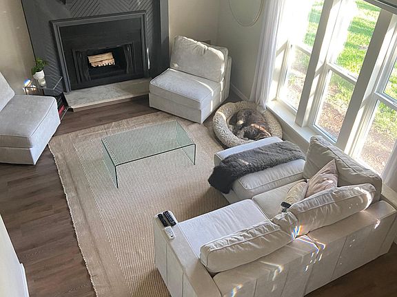 living room with a high ceiling, large fan, plenty of natural light, wood fireplace, and mounted TV