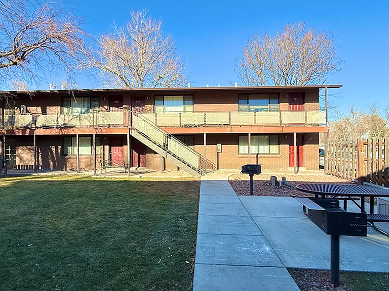 Charming apartment building in a serene neighborhood with inviting outdoor picnic area and manicured lawn.