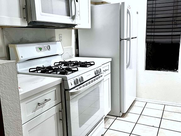 Kitchen: Gas, Oven, Microwave, Refrigerator in very good condition, neat and clean. Tiles on the floor. LED lights on ceiling.