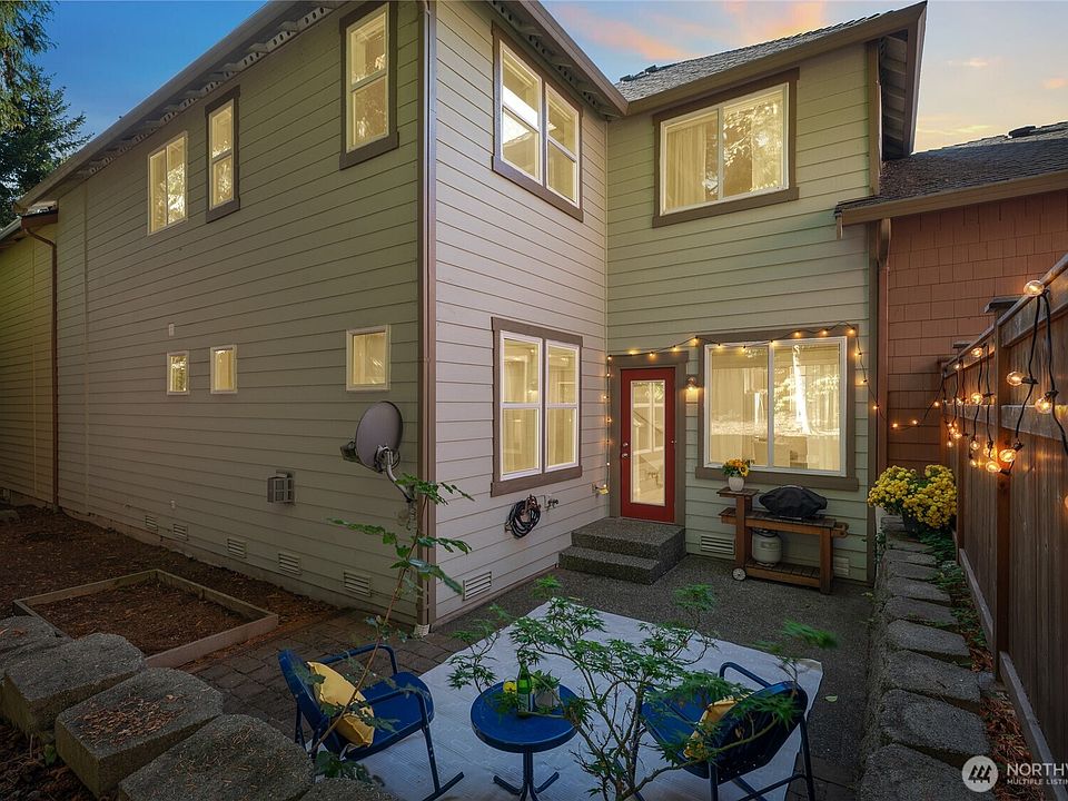 Outdoor seating area perfect for morning coffee, with paved patio, and backyard with garden beds.>