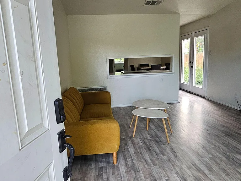 Open living area with durable plank flooring, ceiling fan, and French doors leading to the backyard.