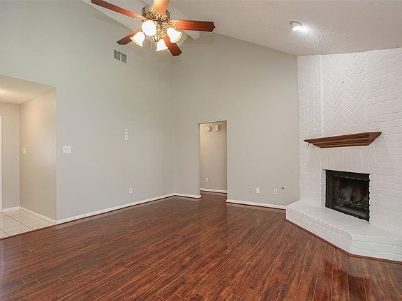 This living room is more like a GREAT room featuring a stunning fireplace, high ceiling, recessed lighting, dark stained ceiling fan, and an amazing wall of windows providing a lovely view of your backyard to keep an eye out on the kids or pets playi