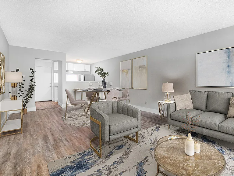 Elegant living room with hardwood floors, modern furniture, and an open dining area leading to a sleek kitchen.