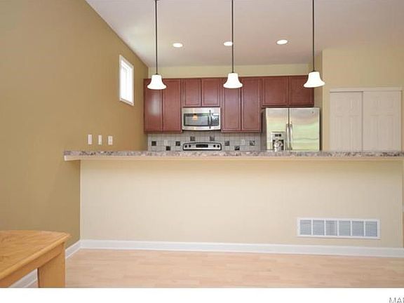 Kitchen with Cherry stained cabinetry, stainless appliances, tile backsplash