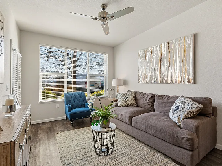 Aspire Apartments Tracy CA A living room with a blue chair and a painting of a tree on the wall.