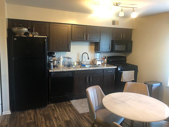 Large dine-in kitchen with track lights, ashy gray laminate floors, espresso cabinets and brushed nickel hardware, upgraded faucet, island/bar area.