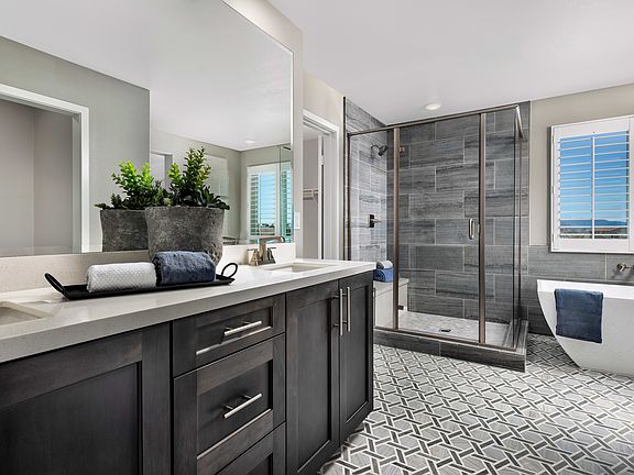A modern and stylish bathroom with a dark vanity, a large shower enclosure, and a tiled floor featur