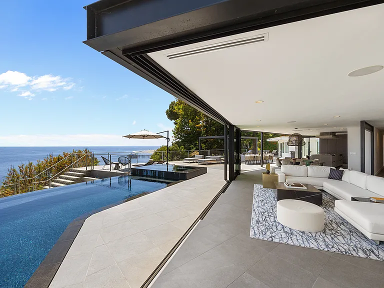 The living room boasts floor-to-ceiling glass doors with breathtaking ocean views.