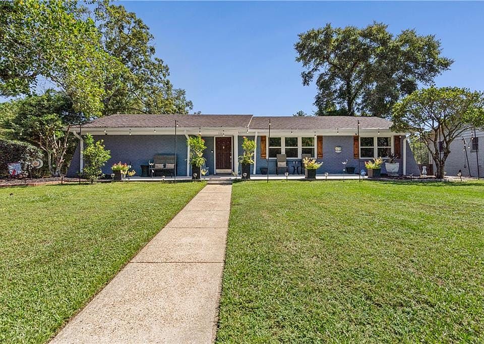 View of front of home with a front lawn, brick siding, and covered porch
