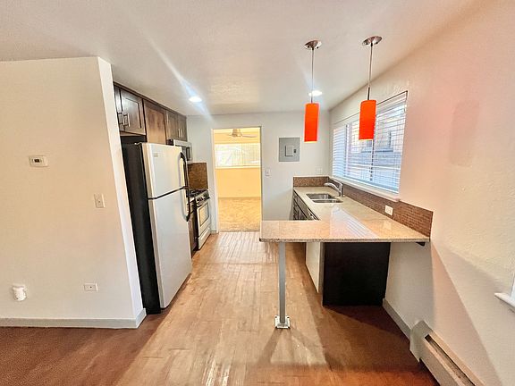 Charming kitchen with modern appliances, elegant granite countertops, and vibrant orange pendant lights.