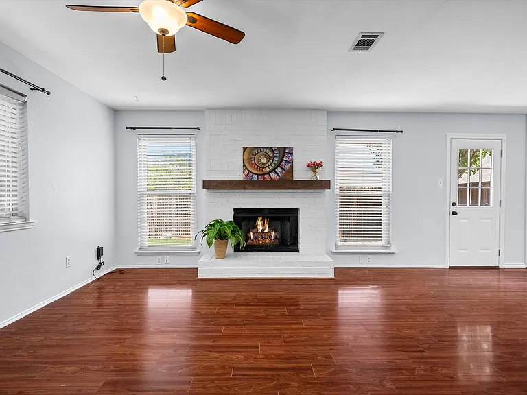 The living room has plenty of natural light and a beautiful fireplace with a brick hearth.