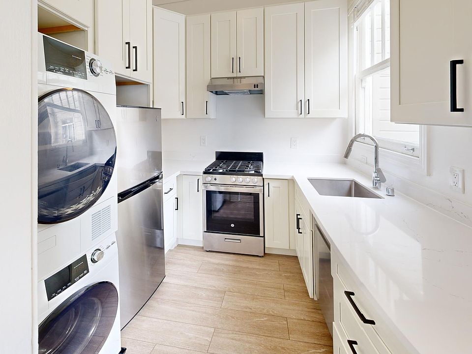 Kitchen with multiple cabinets, refrigerator, stove, range hood, sink, and an in-unit washer and dryer