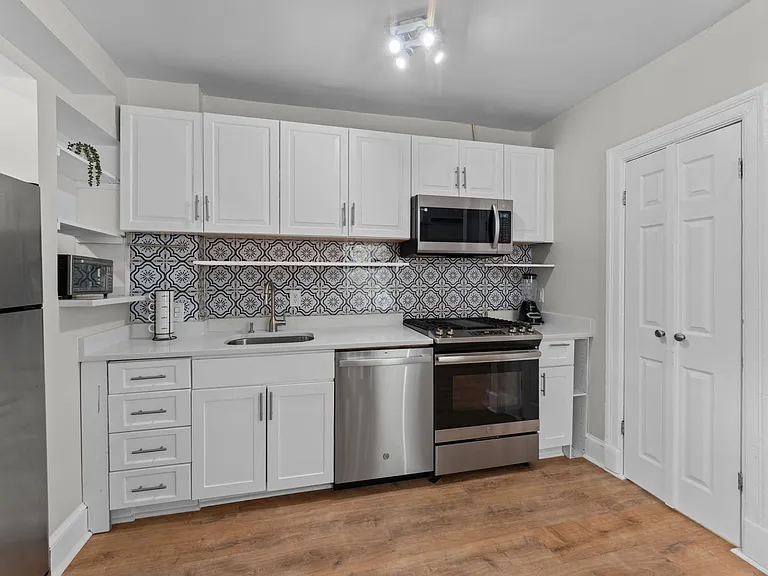 Quartz counters and custom tile backsplash compliment the shelving & cabinetry
