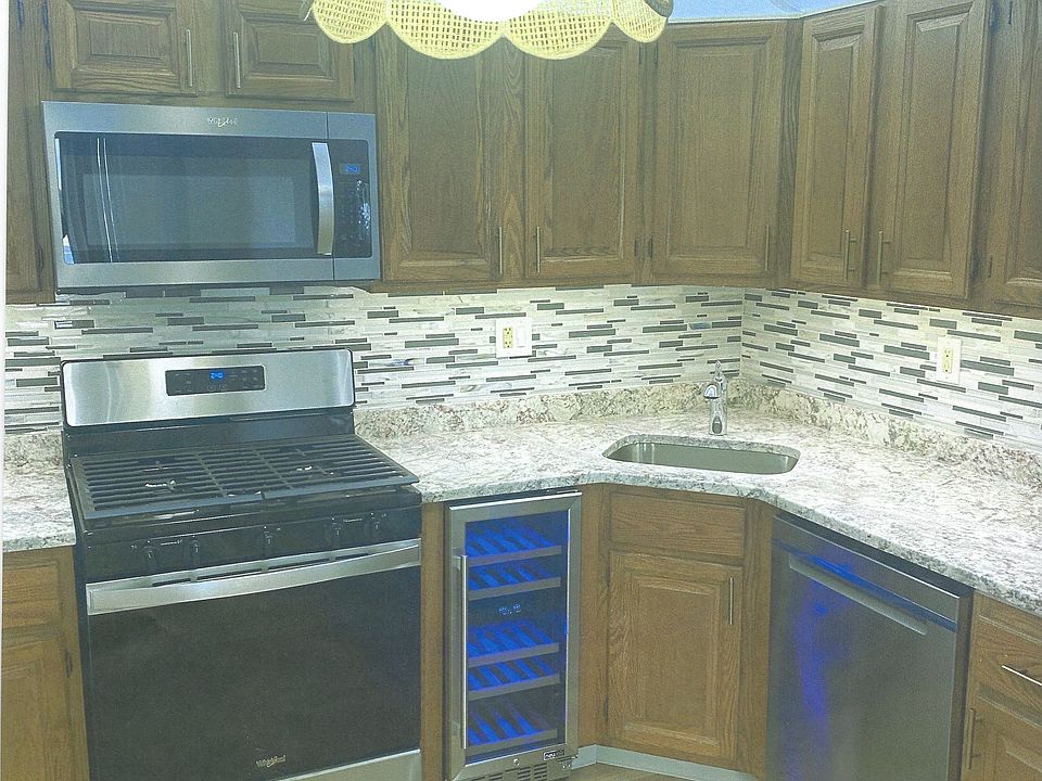 Kitchen with brand new stainless steel appliances including dual temperature wine cooler and stone and glass tile backsplash