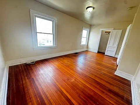 Spacious oversized bedroom overlooking the front porch and street, featuring two large windows that fill the room with natural light. Significantly larger than a standard bedroom, it also includes a walk-in closet for added convenience.