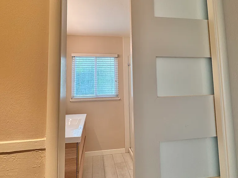 The bathroom is directly across the hall from the primary bedroom. It features a stylish pocket door...