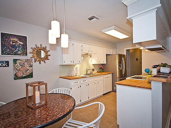 View of breakfast room and kitchen . Freshly painted cabinets. Ceramic tile floor. Butcher block counter tops. Three pendant lights hang in the breakfast room..