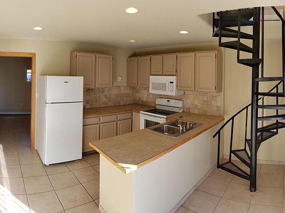 Downstairs kitchen with oven, microwave, and dishwasher. Stairwell to upstairs and door to laundry/spare room.